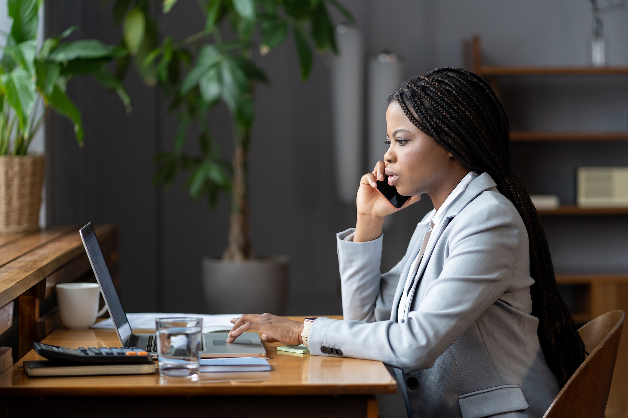 afro-female-business-consultant-interacting-with-client-over-phone-and-entering-data-on-laptop.jpg